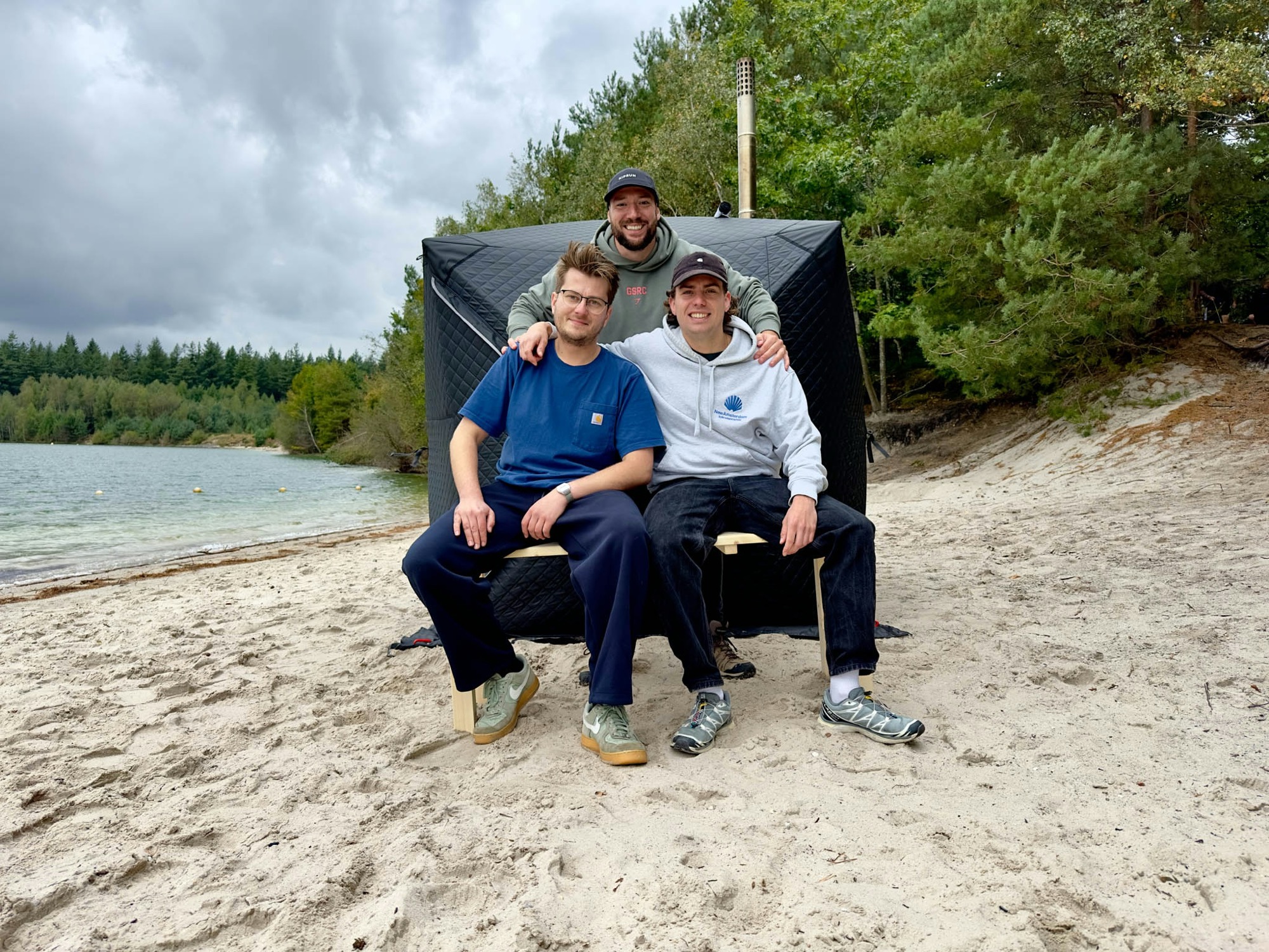 De oprichters van MOOSSE (Aymar, Deniz en Casper) bij een MOOSSE saunatent aan het water